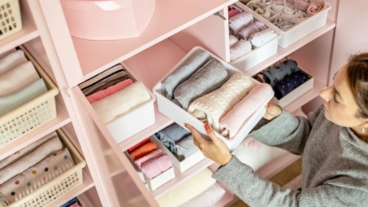 Happy young mother enjoying tidying up at female child wardrobe